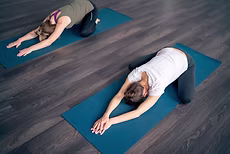 Two people resting in child's pose on yoga mats